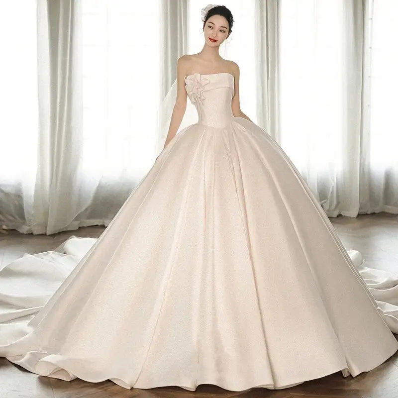 A strapless ivory satin dress with a fitted bodice featuring embroidered floral detail and a big train skirt showcasing luxury women’s fashion.