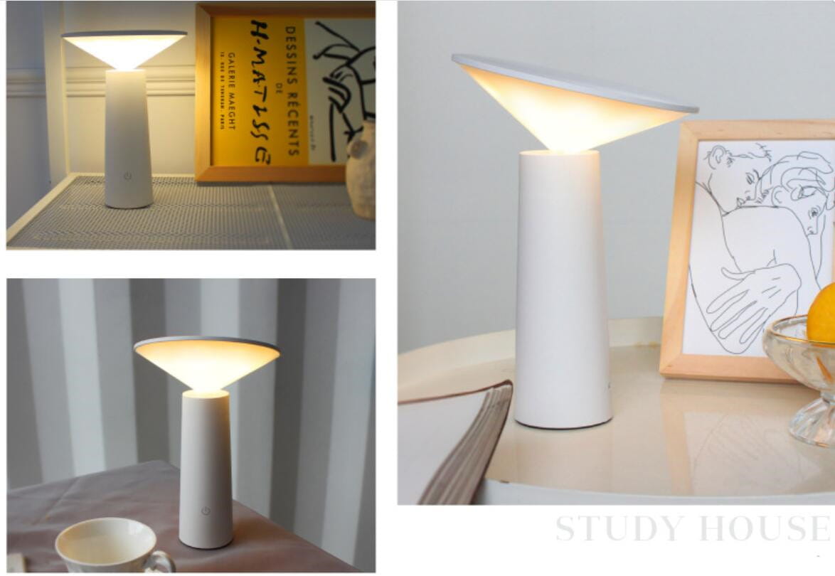 Minimalist touch table lamp usb led with a white cylindrical body and a conical shade emitting warm diffused light ideal for led reading.