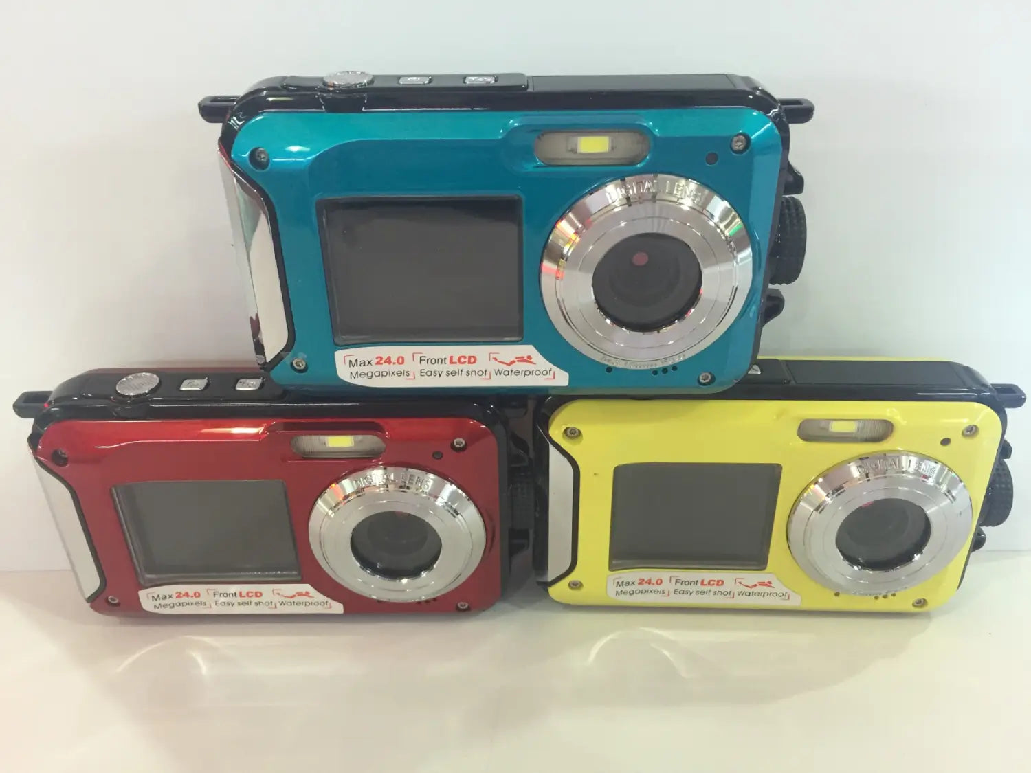 three rugged waterproof selfie digital cameras in vibrant teal red and yellow with silver lens rings and durable plastic casings from royale essence lux