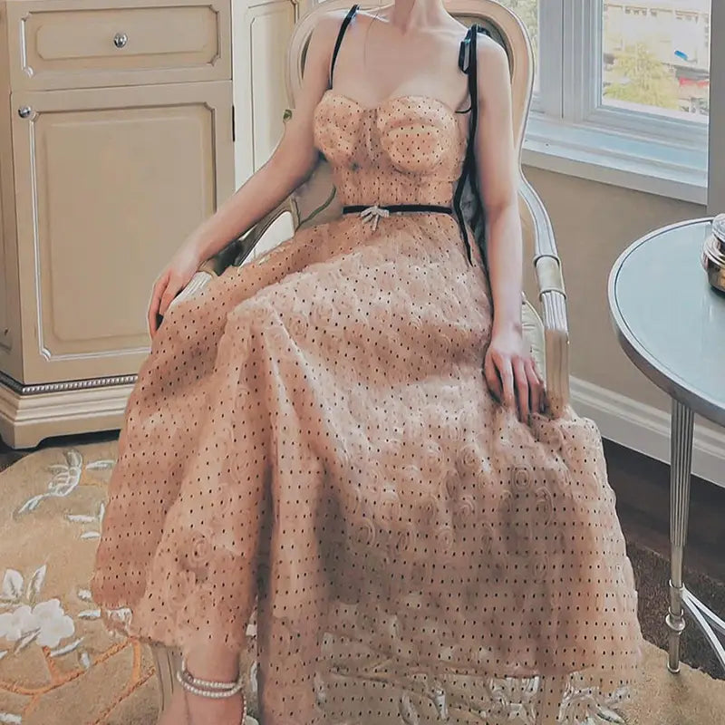 A blush pink lace slim drawstring dress with black straps and matching belt featuring delicate polka dots and layered fabric.