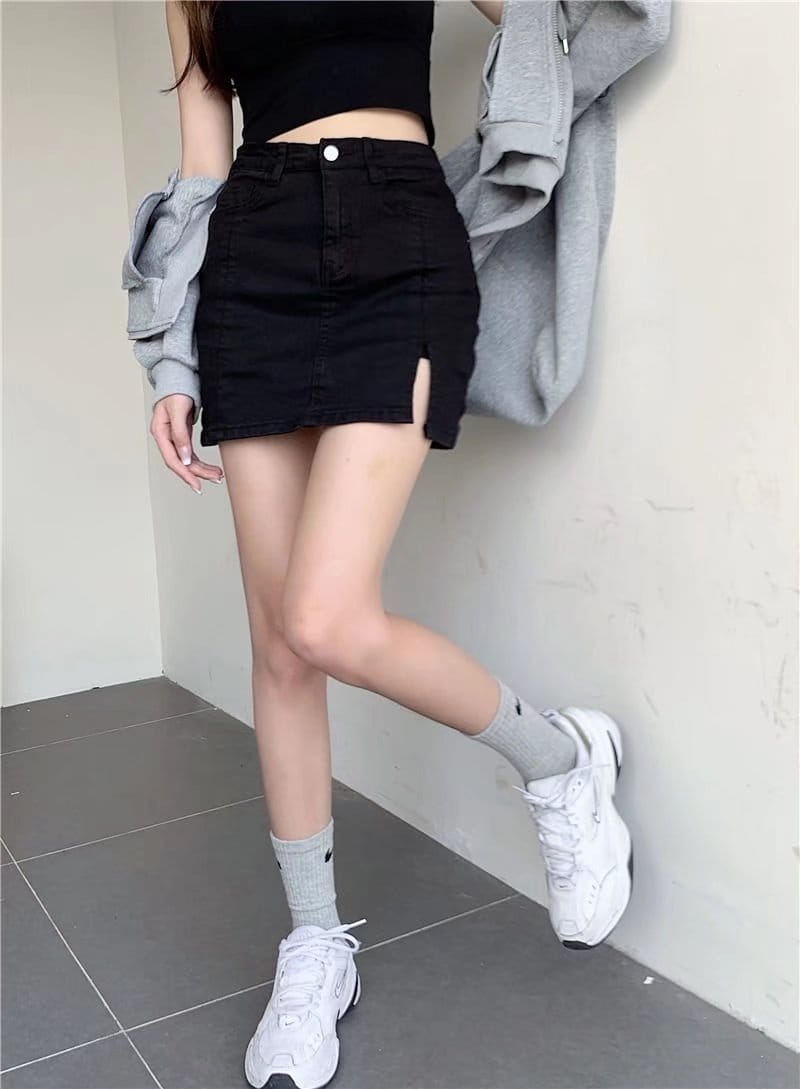 distressed black denim skirt with a front slit made of black denim fabric in a mini length design