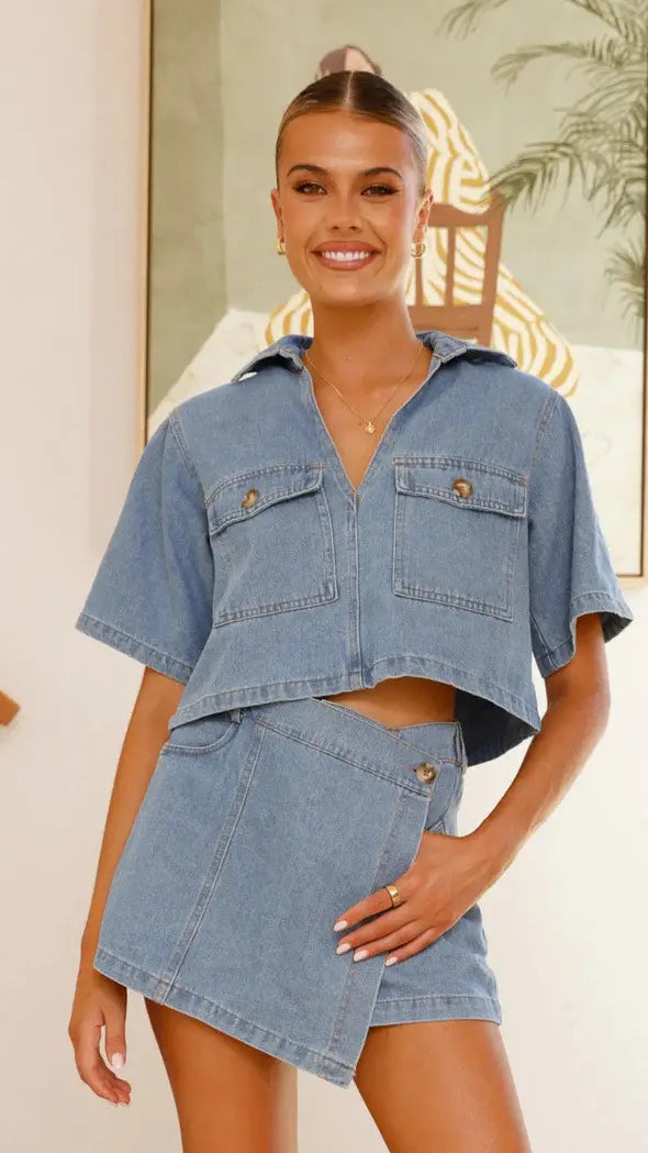 women’s irregular denim short pantskirt suit featuring a light blue denim short sleeve loose cropped shirt with two front pockets and a matching asymmetrical irregular denim short skirt