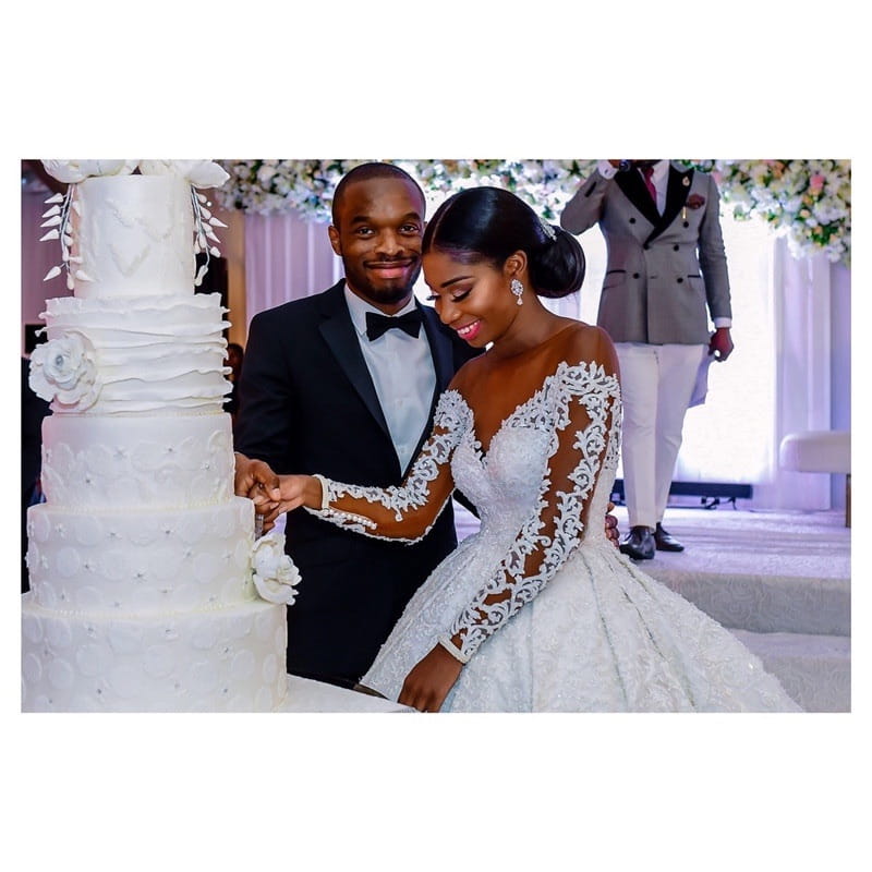 a multi-tiered white wedding cake with delicate floral decorations and textured icing complements a lace long sleeve custom wedding gown for bridal dresses.