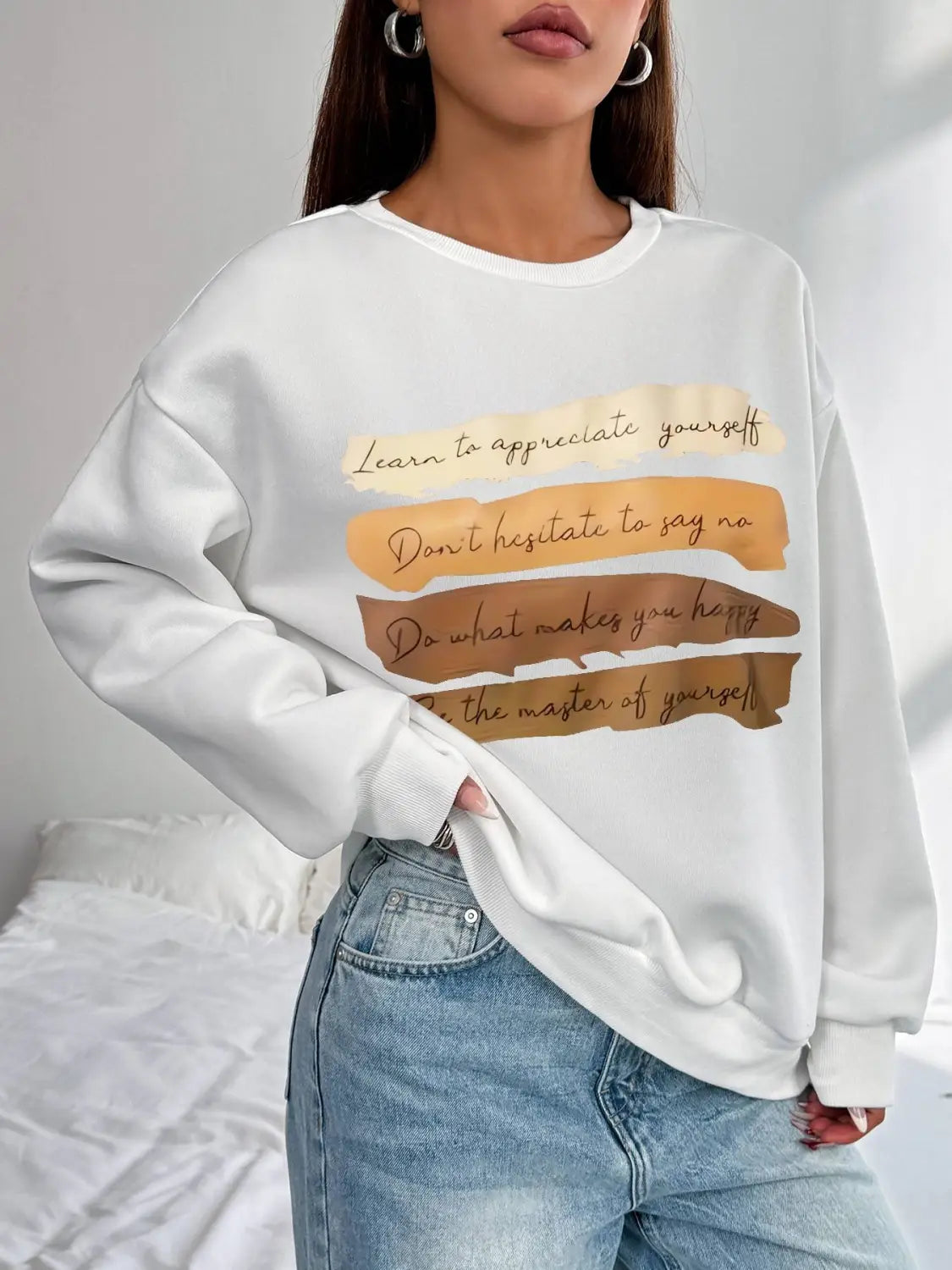 White oversized long sleeve sweatshirt in solid colour featuring a motivational quote printed in gold and brown tones suitable for daily wear.