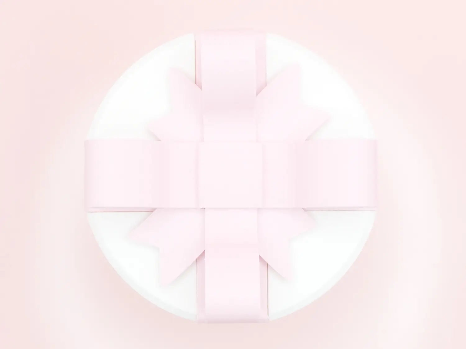 a creative bowknot pink and white valentine day gift box featuring a delicate pale pink ribbon bow tied in a symmetrical cross pattern atop a smooth white circular base