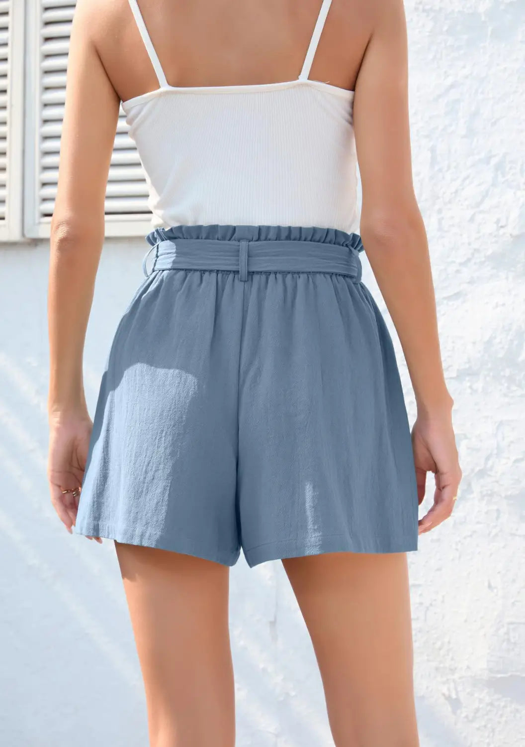 Light blue high-waisted shorts with a ruffle bow waist tie and matching belt featuring pockets in a fashion ruffle bow style.