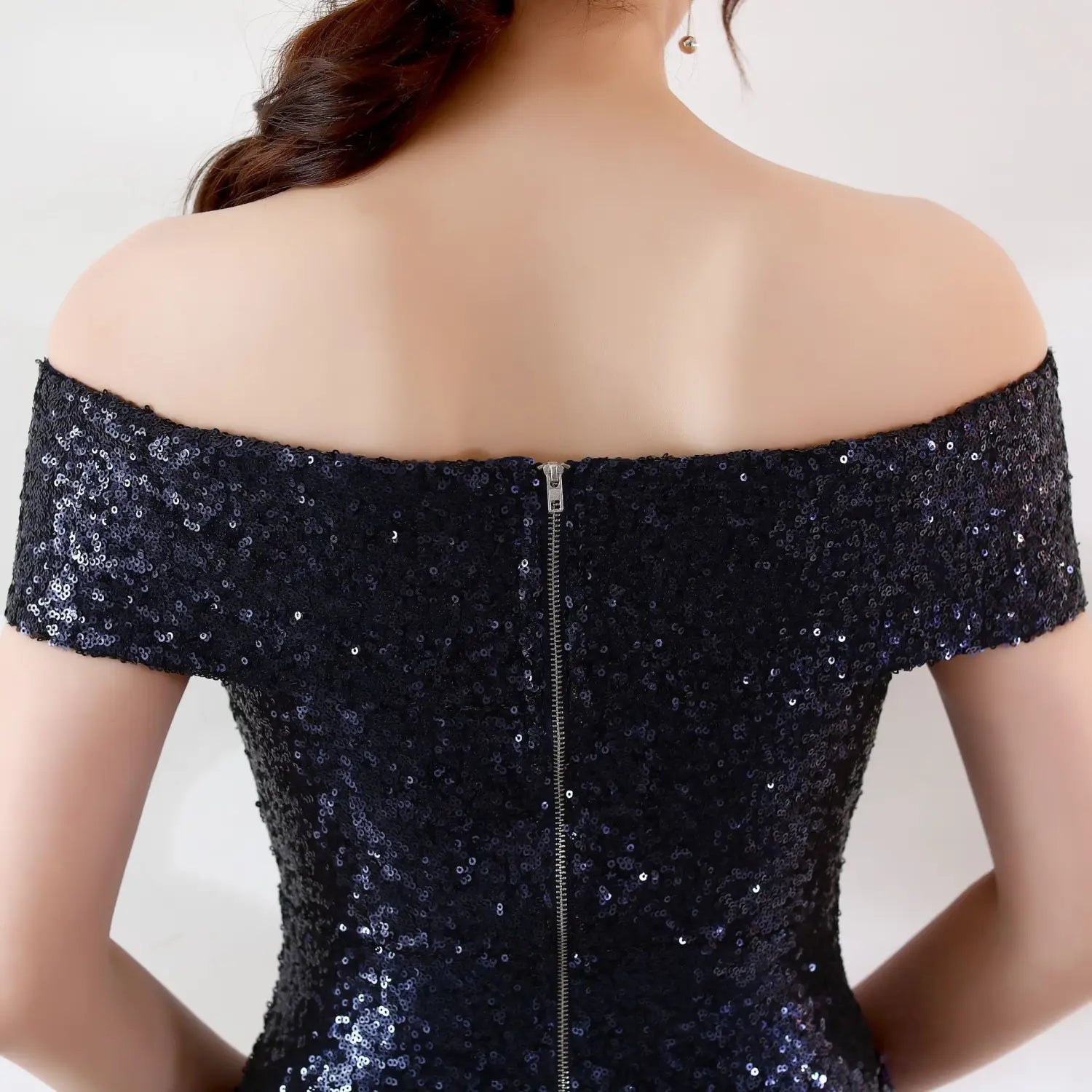 A shimmering black sequined off-the-shoulder birthday party dress with a central zipper down the back designed as a slimming host gown.