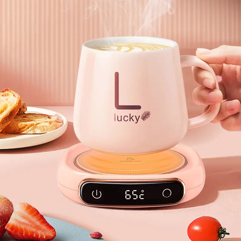 pink ceramic mug with black l lucky logo and feather design sitting on a matching pink milk heating insulation base desktop digital display showing 65 degrees celsius temperature