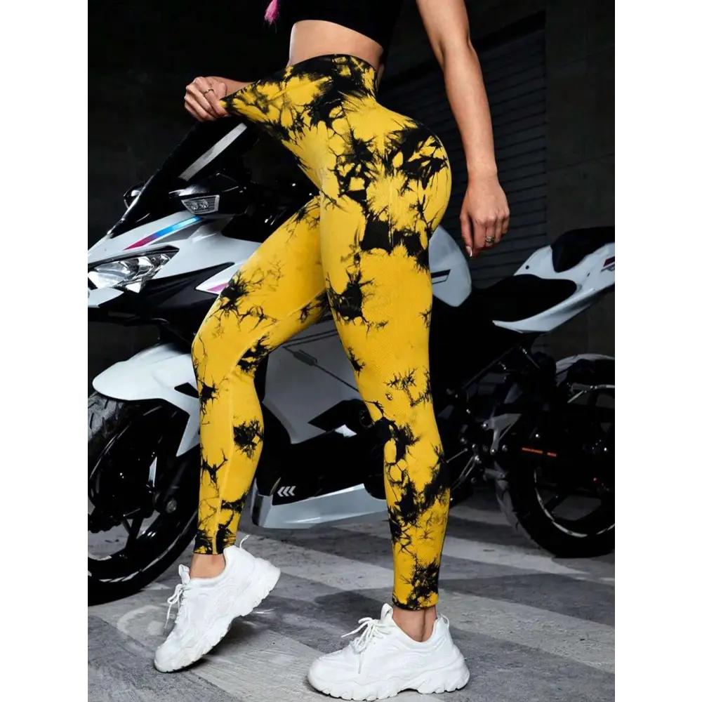 Bright yellow tie dye high waist seamless leggings with black splatter patterns made of stretchy athletic fabric for butt lift