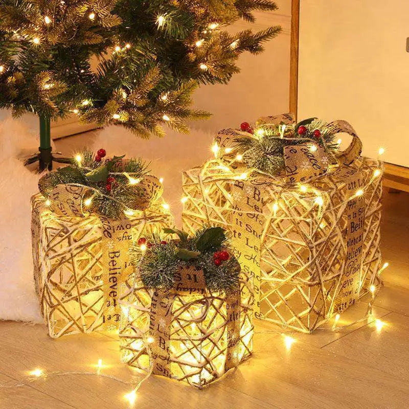Three warm white led woven gift boxes wrapped in rustic burlap with festive greenery accents for christmas decor