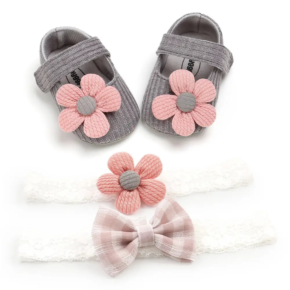 gray knit baby shoes with pink fabric flowers and a matching plaid bow headband designed as white flower princess shoes for baby and toddler use