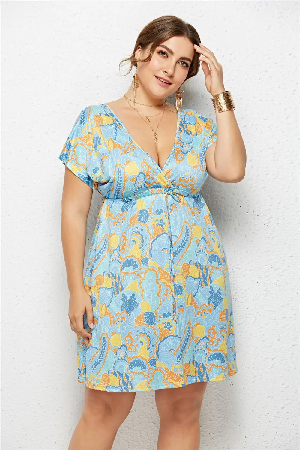 A light blue and yellow geometric printed short-sleeved dress with a deep v-neck and elastic waist tie design.