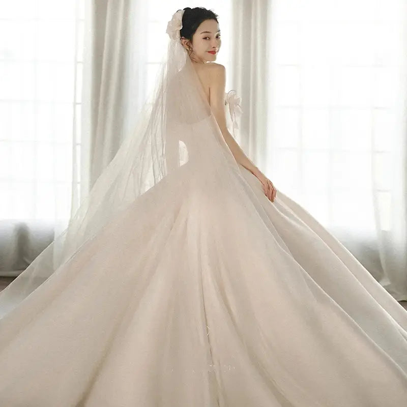 A flowing ivory satin strapless dress with a fitted bodice and a big train in luxury women’s fashion.