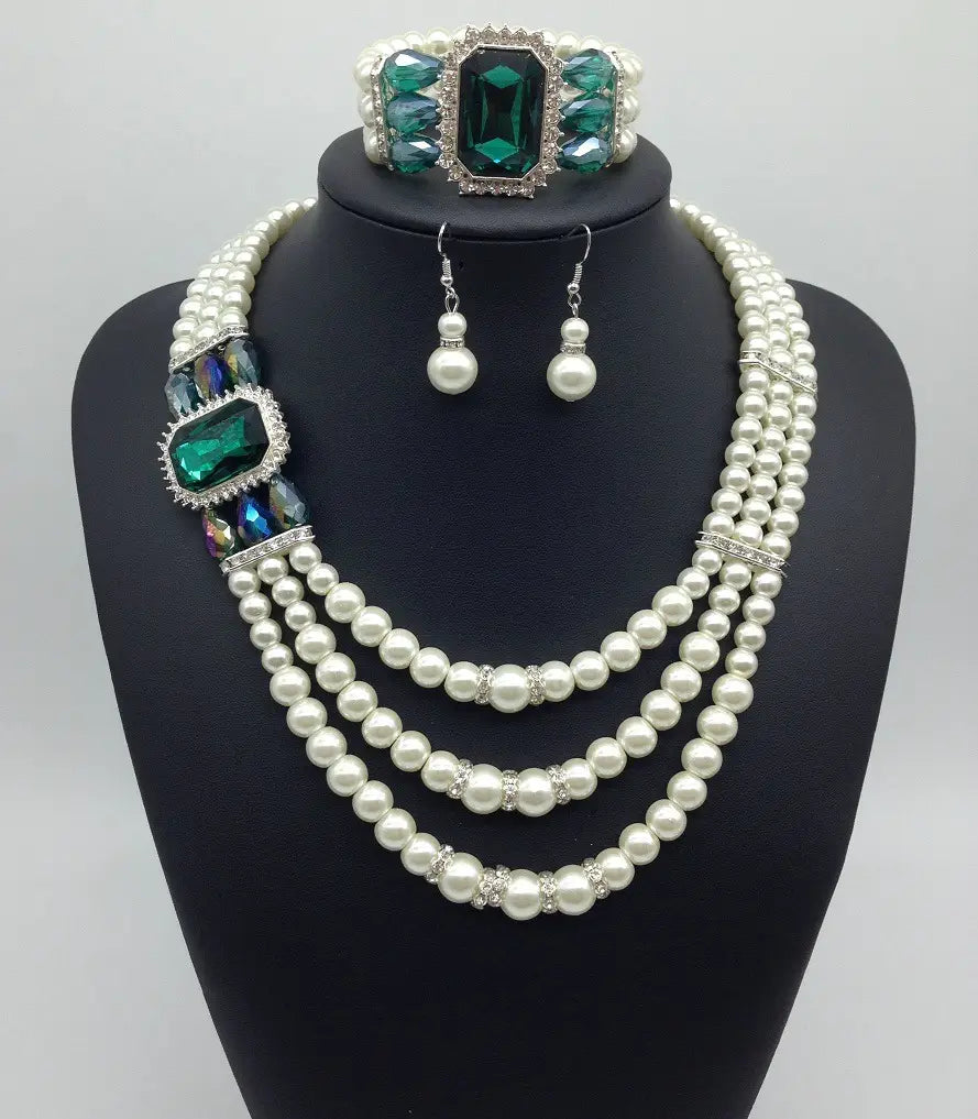 a european fashion diamond gemstone pearl jewelry set featuring a three-strand pearl necklace with silver-toned accents and emerald green gemstones, paired with matching earrings and a coordinating bracelet