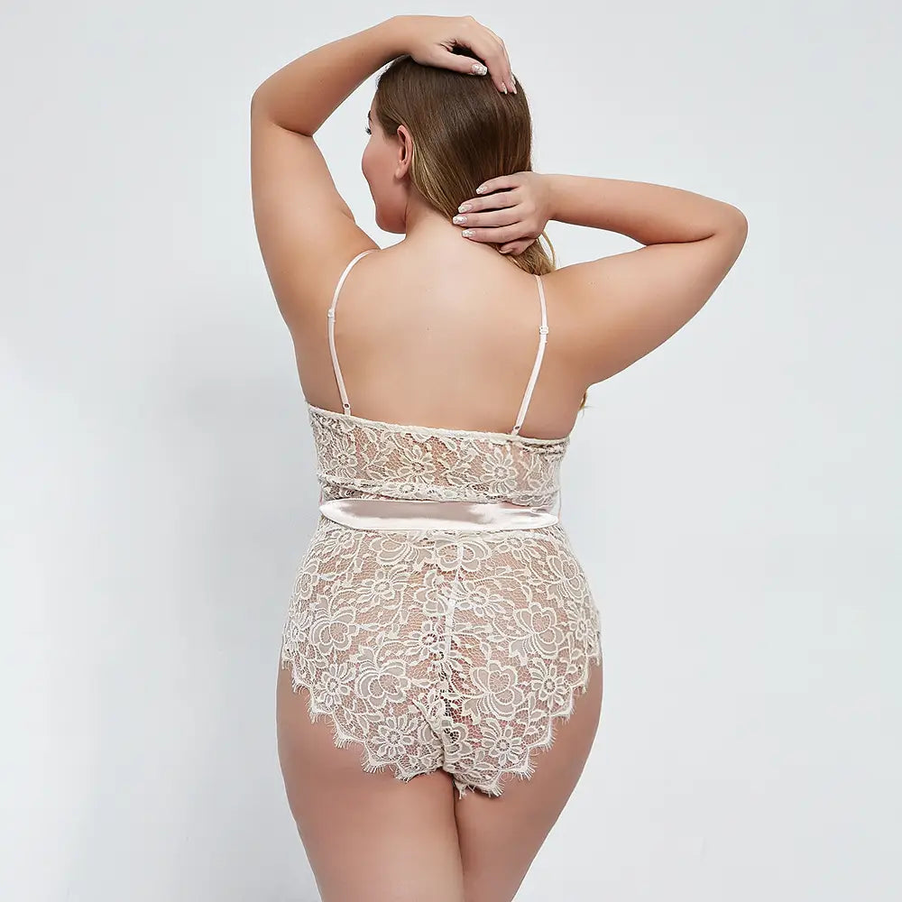 Beige oversized lace lace bodysuit with thin spaghetti straps and a satin ribbon belt made of floral lace material.