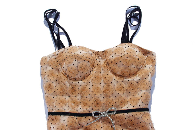 A beige strapless corset top with delicate rose appliqués and black polka dots, featuring a sparkling silver bow at the waist, paired with a blush pink lace slim drawstring dress.