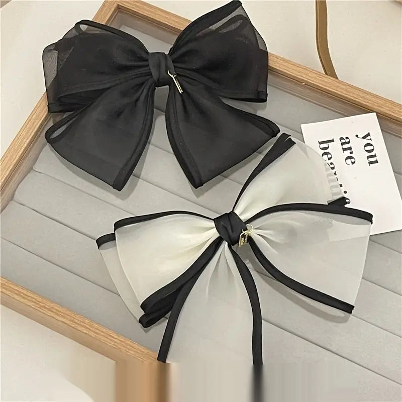 Elegant black and white handmade mesh bow hair clips featuring sheer fabric with satin trim designed for women.
