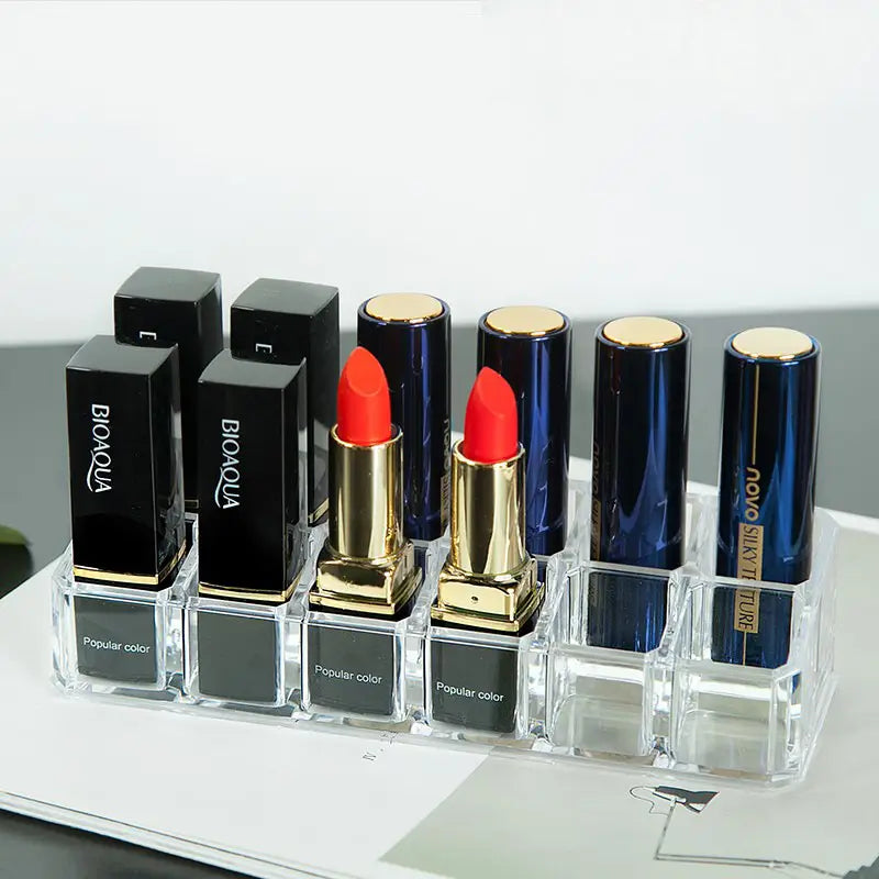 Clear acrylic makeup organizer with compartments holding multiple lipsticks in black and blue cases with gold caps organizer image.