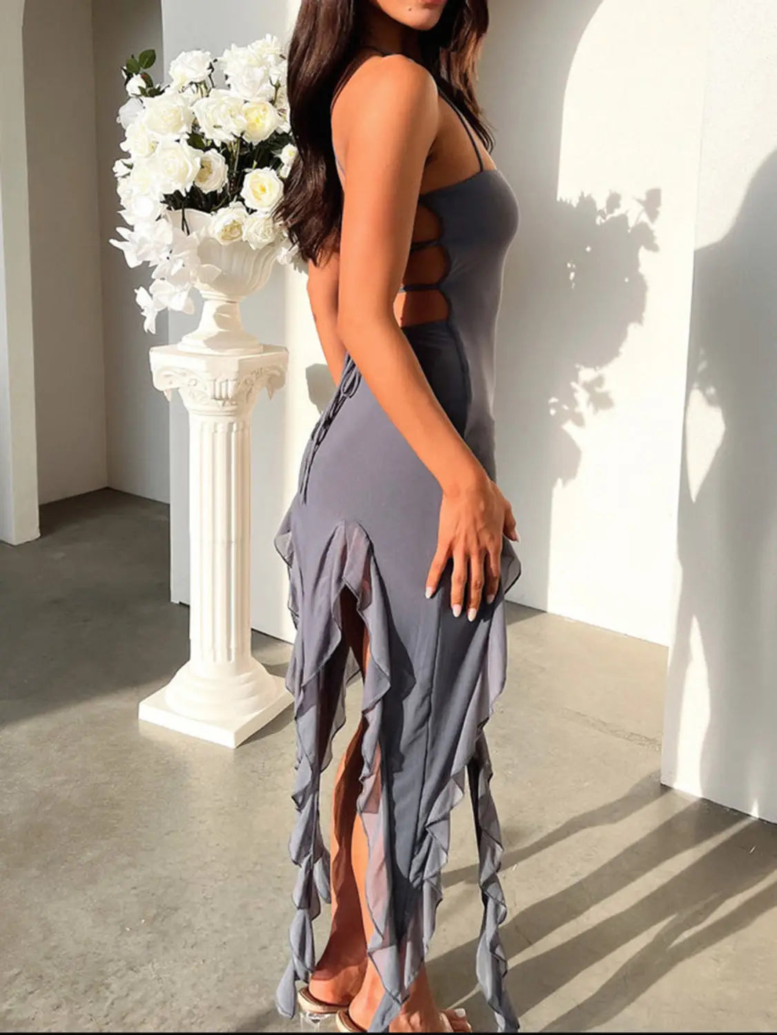 a sleek gray sleeveless suspender tight slim dress with a back cutout and ruffled hemline showcasing the back side of the sexy suspender tight skirt