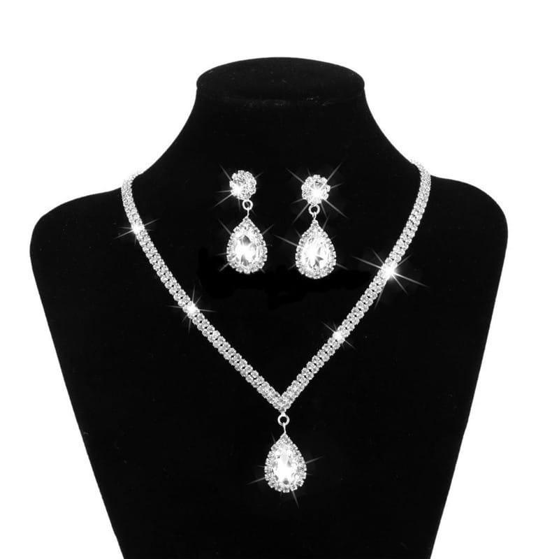 Silver v-shaped crystal bridal jewelry set featuring a sparkling silver crystal necklace with matching teardrop earrings and a dangling pendant.