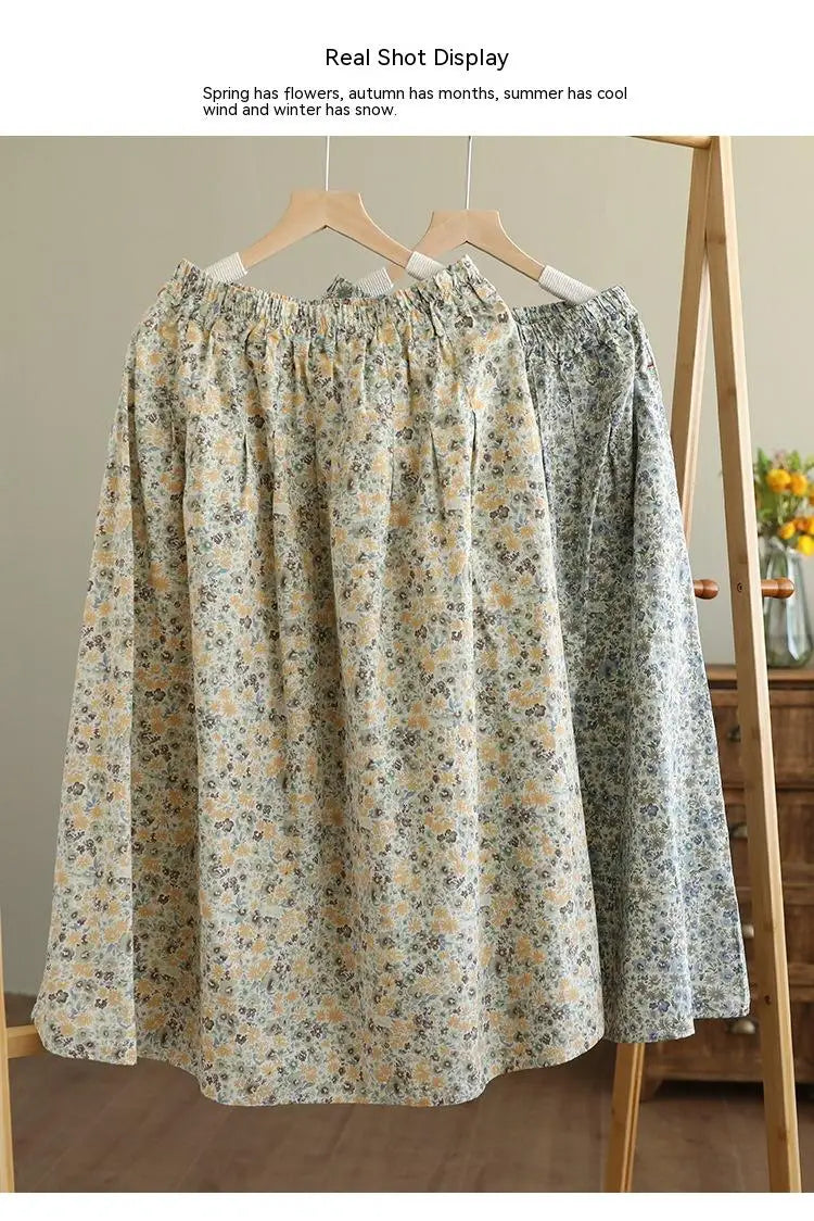 a soft flowing artistic floral washed cotton midi skirt in pale yellow and green pattern hanging on wooden hangers