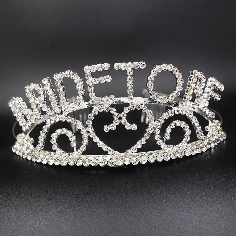 a sparkling silver rhinestone bridal headband featuring an ornate design with the word queen spelled out, a luxury women’s fashion hair accessory.