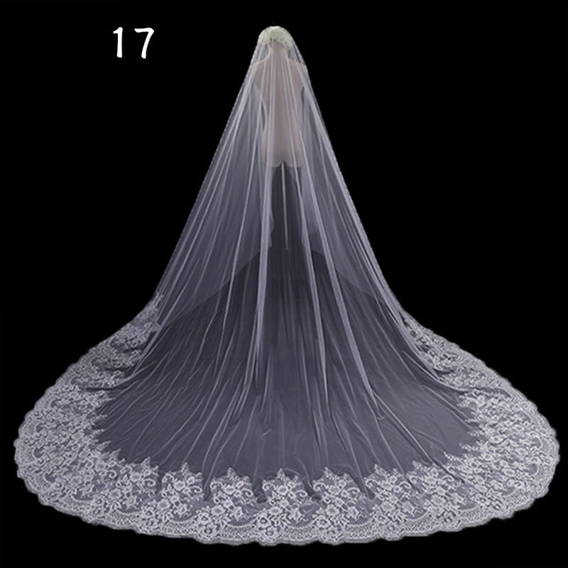 A delicate white lace bridal veil with flowing sheer fabric and intricate floral embroidery along the hem in a long lace wedding veil meters wide style.