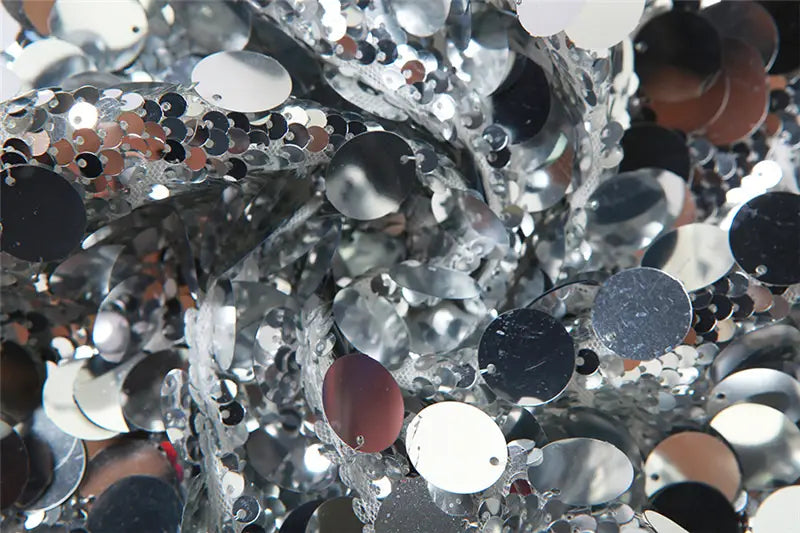 a pile of shimmering silver and black sequins with reflective circular surfaces for a halter backless sequined vest highlighting the backless sequined design and sparkling material