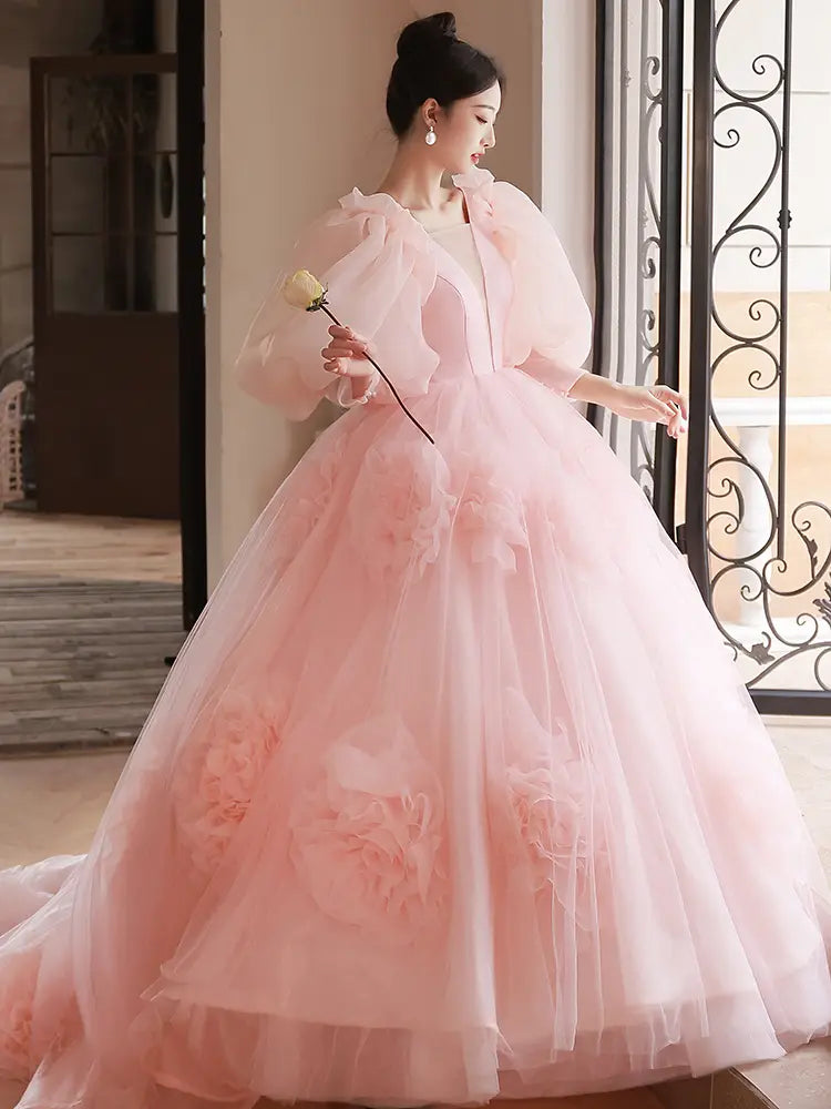 A delicate pink tulle ball gown with voluminous puffed sleeves and floral appliqués designed for a high end banquet style host.
