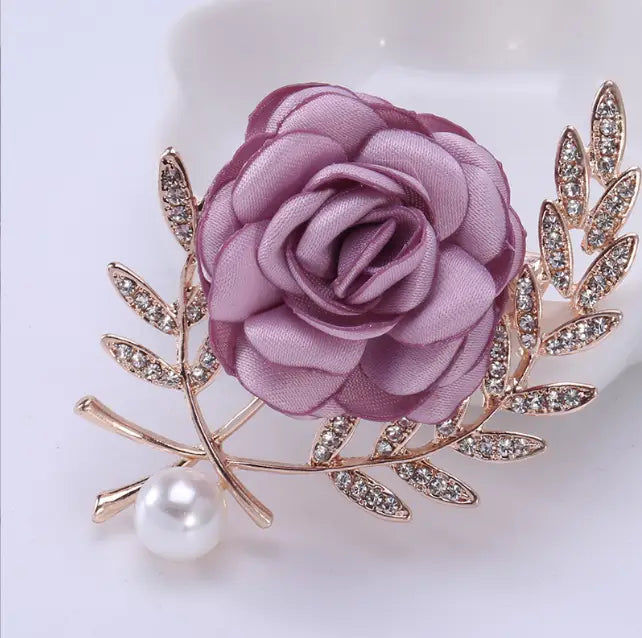 a delicate lavender satin fabric flower lady brooch with gold-toned leaf accents embedded with clear crystals and a dangling white pearl from the flower lady temperamental pin floral brooch set