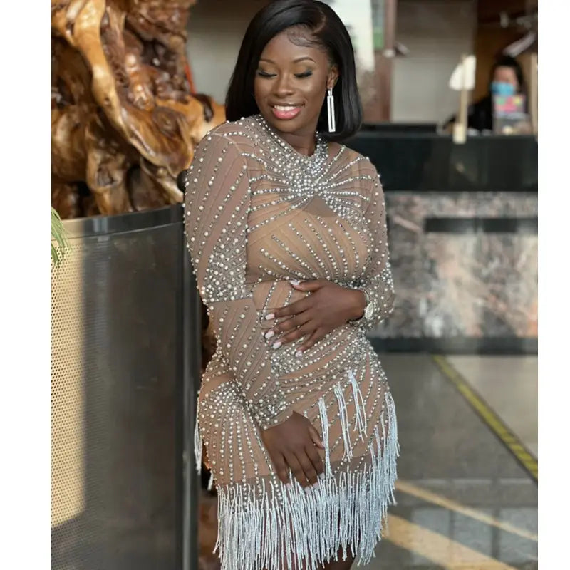 A shimmering beige sheer beaded tassel dress with intricate silver beading and delicate white fringe detailing designed for a birthday party long sleeve occasion.