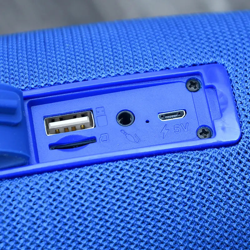 blue textured fabric strap wireless bluetooth speaker back side showing plastic panel with usb micro-usb and 3.5mm audio ports