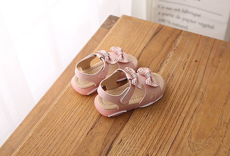 pink children’s sandals with delicate bow details on the straps designed as white led flashing princess shoes featuring cute flower flashing lights