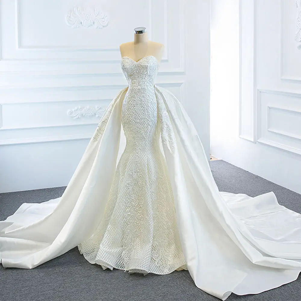 A white lace mermaid wedding dress wears two fishtail train with intricate lace detailing and a flowing train.