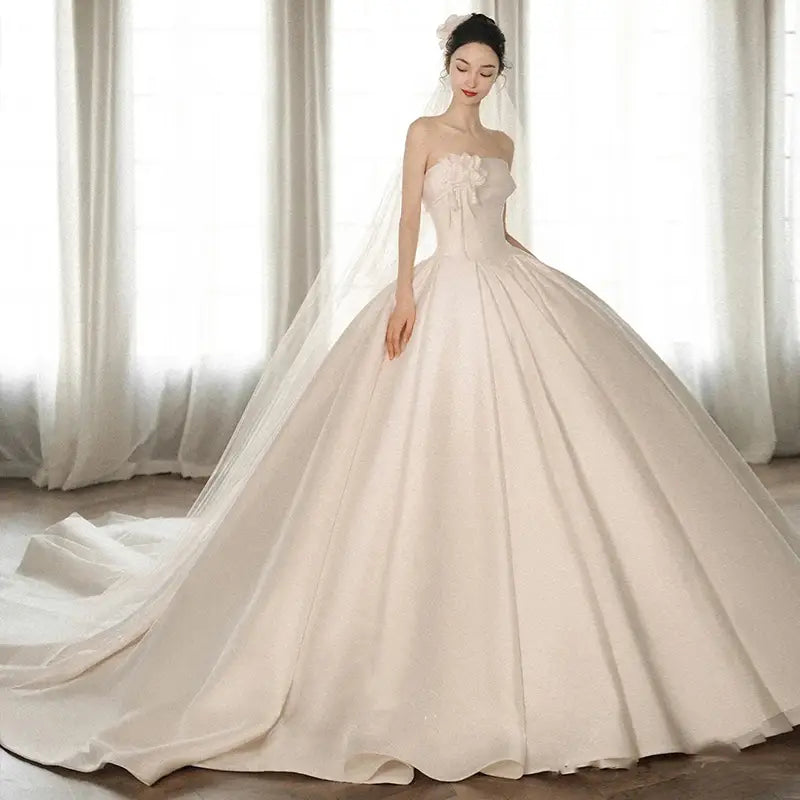 A flowing ivory satin strapless dress with an embroidered floral embellishment on the bodice and a big train in luxury women’s fashion.