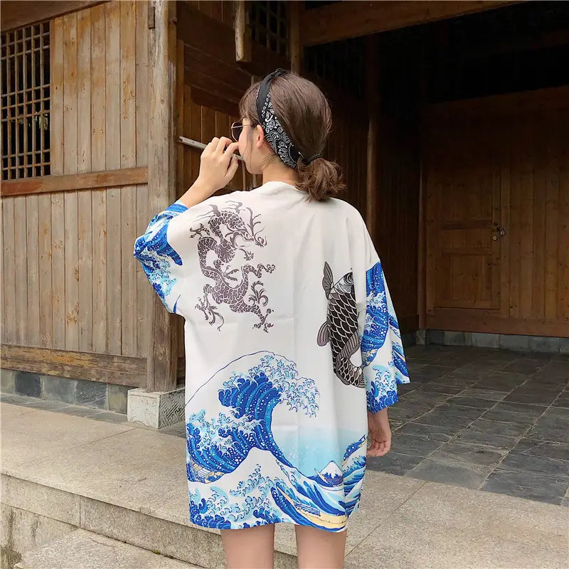 White kimono-style shirt with bold blue and black wave dragon and fish prints designed as sun protection clothing for effective coat sun protection.