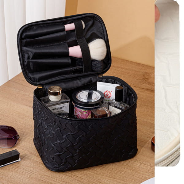 Black premium large capacity cosmetic bag with woven texture and interior compartments holding brushes and beauty products.