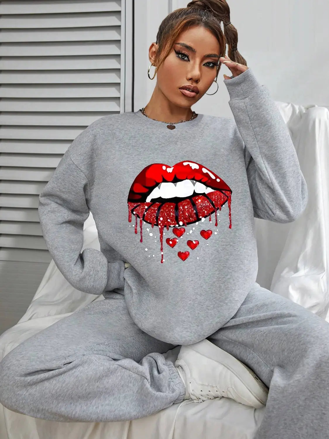 Gray pocketed long sleeve sweatshirt featuring a bold red glittery lip graphic with a dripping effect and small hearts below.
