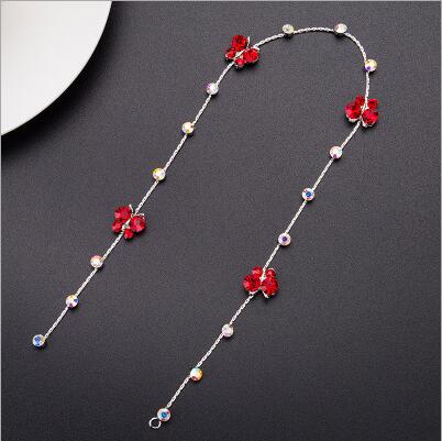 a delicate silver chain wedding hair accessory adorned with vibrant red floral charms and scattered pearls for bridal hair styling