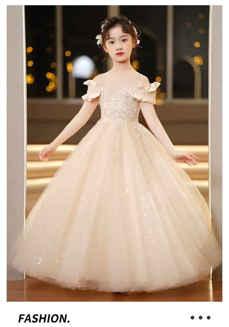 A delicate off-the-shoulder blush spandex princess dress for girls featuring ruffled sleeves, a sparkling champagne sequined bodice, and a layered tulle tutu.