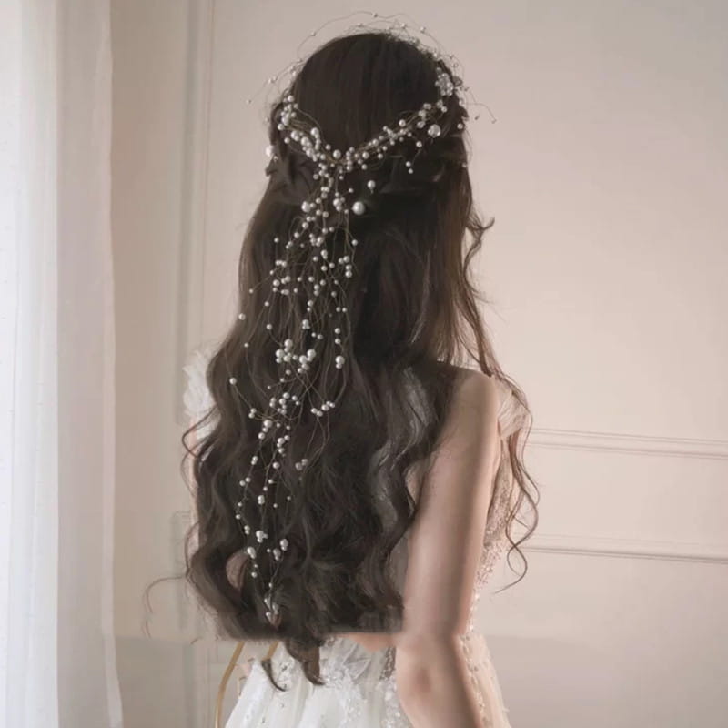 a delicate silver bridal headdress handmade with cascading pearls and tiny crystals elegantly draped over dark wavy hair showcasing a handmade pearl fairy design