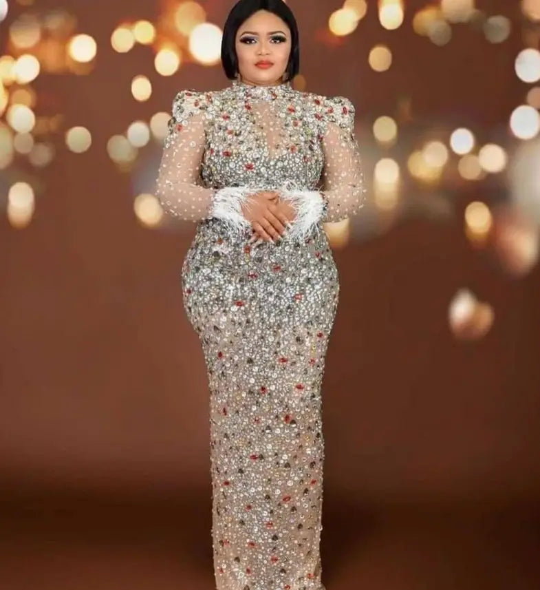 silver feathered rhinestone mesh stretch slim dress featuring a shimmering silver gown with intricate beading, sparkling embellishments, sheer long sleeves, and a fitted silhouette.