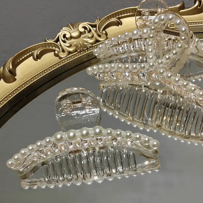Transparent pearl grab clip made of clear acrylic with a row of white pearls and sparkling rhinestone bow accents is a clip gentle transparent accessory.