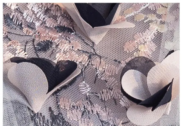 delicate cream and black paper heart ornaments rest on textured lace fabric with pink and silver embroidery alongside a light blue floral vocal choral art exam long skirt.