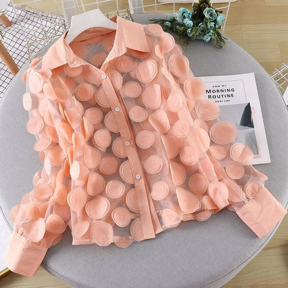 A delicate peach-colored chiffon gauzy shirt with 3D flower chiffon gauzy detailing for an elegant layered look