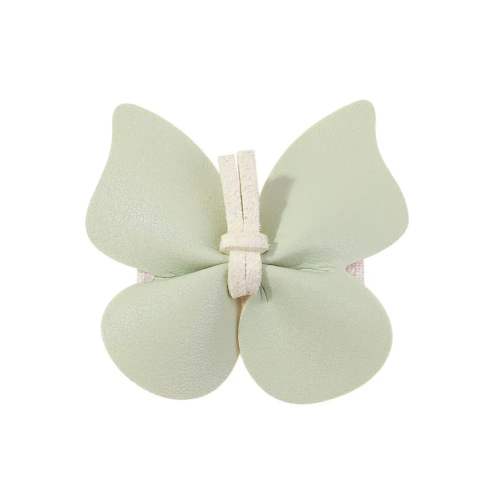 A delicate mint green leather butterfly bag clip children’s barrette made of soft leather with a white cord tied through the center.