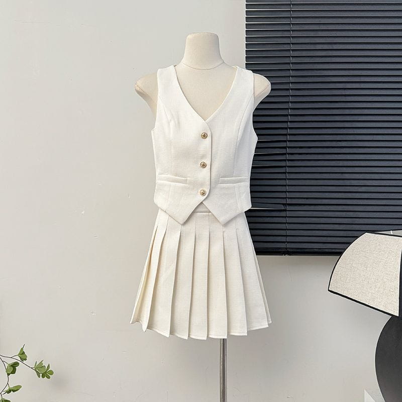 white sleeveless v-neck vest with gold buttons and matching high waist pleated skirt two-piece set displayed on a mannequin