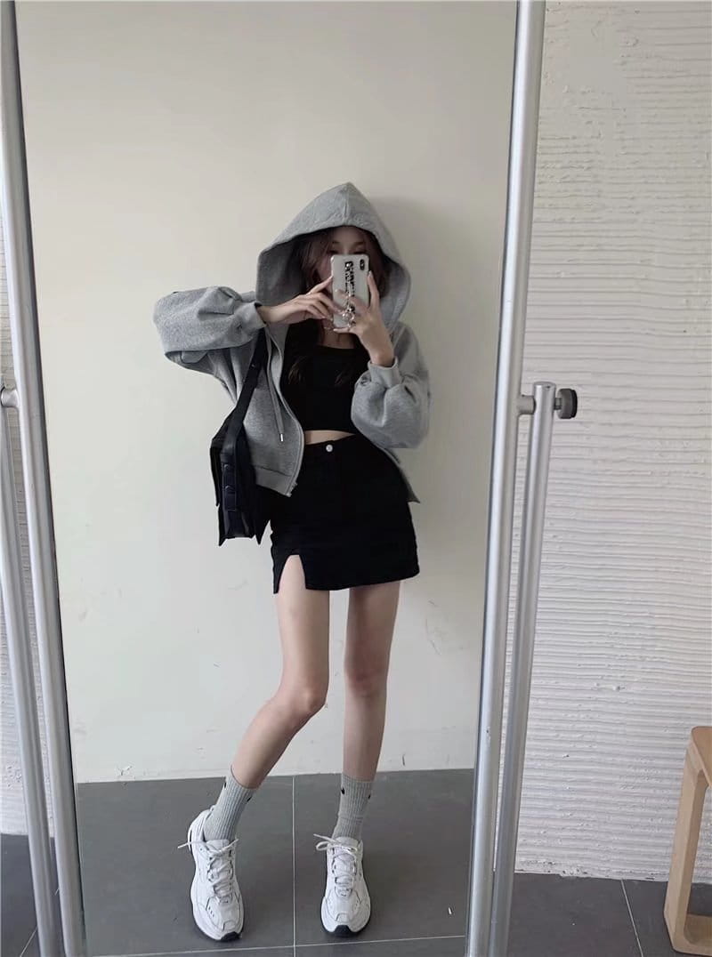 gray hooded sweatshirt with loose fit and drawstring detailing paired with distressed black denim skirt featuring a side slit