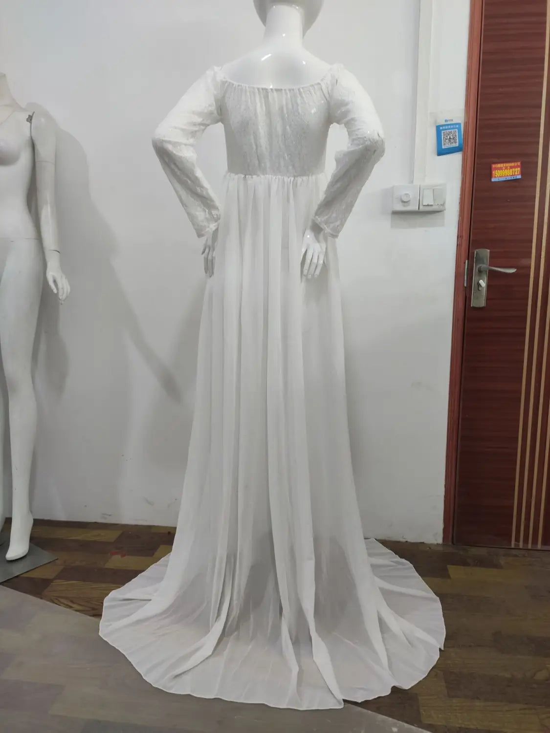 a flowing american white sexy long sleeve maternity dress with a sheer overlay and main fabric lace displayed on a mannequin