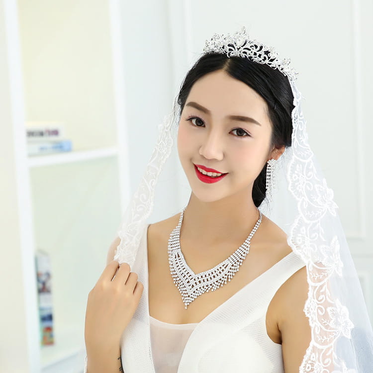 A sparkling silver tiara with intricate lace detailing and a delicate veil featuring an american rhinestone claw chain and rhinestone claw chain large.